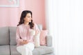 Beautiful young Asian woman drinking coffee when sitting on sofa Royalty Free Stock Photo