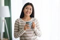 Beautiful Young Asian Woman Drinking Coffee While Standing Near Window At Home Royalty Free Stock Photo