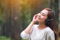 A beautiful woman enjoy listening to music with headphone with feeling happy and relaxed in the park Royalty Free Stock Photo