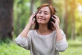 A beautiful woman enjoy listening to music with headphone with feeling happy and relaxed in the park Royalty Free Stock Photo