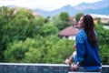 A beautiful young asian woman enjoyed sitting by swimming pool with green nature background