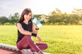 Beautiful young Asian woman exercising in the morning at a running track, taking a rest to drink water Royalty Free Stock Photo