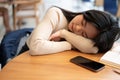 A beautiful young Asian woman is falling asleep on a table in a library or coffee shop Royalty Free Stock Photo