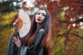 Beautiful young Asian woman with fan on background of red maple Royalty Free Stock Photo