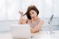 Beautiful young Asian woman having her hair cut at home the during coronavirus pandemic, online hairdressing with laptop computer Royalty Free Stock Photo