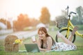 Beautiful young Asian woman having picnic on sunny spring day in park, happy reading things on internet, having cup of coffee, Royalty Free Stock Photo