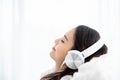 Beautiful young asian woman in headphones listening to music and lying down on bed Royalty Free Stock Photo