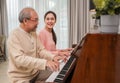 Beautiful young Asian woman and her father sitting playing piano together happy in the living room at home Royalty Free Stock Photo