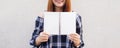 Beautiful young asian woman hiding behind a blank mock up book on concrete wall background. Vintage effect style pictures. Royalty Free Stock Photo