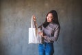 A beautiful young asian woman holding and carrying a white fabric tote bag for reusable and environment concept Royalty Free Stock Photo