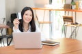 Beautiful young asian woman holding a credit card and shopping online with using laptop computer Royalty Free Stock Photo