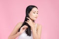 Beautiful young Asian woman holding her healthy hair and combing her hair on pink background Royalty Free Stock Photo