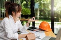 Beautiful young Asian woman holding house model while sitting in front of her working place Royalty Free Stock Photo