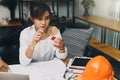 Beautiful young Asian woman holding house model while sitting in front of her working place Royalty Free Stock Photo