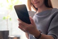 A beautiful young asian woman holding and using mobile phone while drinking coffee Royalty Free Stock Photo