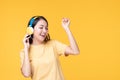 Beautiful young asian woman joyful listening to music on headphones isolated on pastel yellow wall background studio portrait Royalty Free Stock Photo