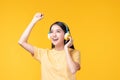 Beautiful young asian woman joyful listening to music on headphones isolated on pastel yellow wall background studio portrait Royalty Free Stock Photo