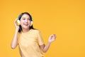 Beautiful young asian woman joyful listening to music on headphones isolated on pastel yellow wall background studio portrait Royalty Free Stock Photo