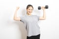 Beautiful young Asian woman lifting dumbbells smiling and energetic isolated over white background.