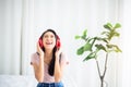 Beautiful young asian woman listening to music with headphones while sitting in bedroom Royalty Free Stock Photo