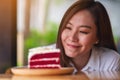 A beautiful young asian woman looking at a piece of red velvet cake in wooden tray on the table Royalty Free Stock Photo