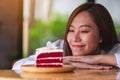 A beautiful young asian woman looking at a piece of red velvet cake in wooden tray on the table Royalty Free Stock Photo