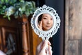 beautiful young asian woman looks at herself in the mirror, hand on cheek. Royalty Free Stock Photo