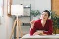 A beautiful young Asian woman is lying on a sofa, writing in her diary with a pen and notebook in her hands. She is a Royalty Free Stock Photo