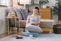 A beautiful young Asian woman is lying on a sofa, writing in her diary with a pen and notebook in her hands. She is a Royalty Free Stock Photo