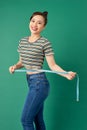 Beautiful young Asian woman measuring her waist with a measure tape over green background Royalty Free Stock Photo