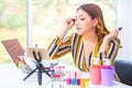 Beautiful young Asian woman putting her make up on during her online beauty product review at home Royalty Free Stock Photo