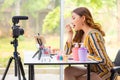 Beautiful young Asian woman putting lipstick on during her beauty products online review on a video blog at home Royalty Free Stock Photo