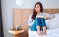 A beautiful young asian woman reading book in a white cozy bed at home Royalty Free Stock Photo