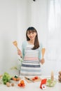 Beautiful young asian woman reading cooking recipe or watching show while making salad Royalty Free Stock Photo