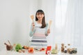 Beautiful young asian woman reading cooking recipe or watching show while making salad Royalty Free Stock Photo