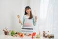 Beautiful young asian woman reading cooking recipe or watching show while making salad Royalty Free Stock Photo