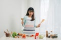 Beautiful young asian woman reading cooking recipe or watching show while making salad Royalty Free Stock Photo