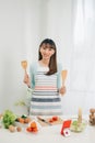 Beautiful young asian woman reading cooking recipe or watching show while making salad Royalty Free Stock Photo