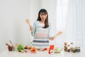 Beautiful young asian woman reading cooking recipe or watching show while making salad Royalty Free Stock Photo