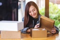 A beautiful young woman receiving and opening a postal parcel box at home for delivery and online shopping concept Royalty Free Stock Photo