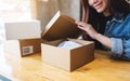 A beautiful young woman receiving and opening a postal parcel box at home for delivery and online shopping concept Royalty Free Stock Photo