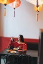 Beautiful young asian woman in red clothes eating asian food in festive chinese vietnamese restaurant colorful paper lanterns