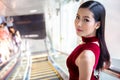 Beautiful young asian woman in red dress going down the escalator in shopping mall . happy elegant lady . copy space