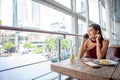 Beautiful young asian woman in red dress sitting in the restaurant looking out the window calling with smartphone . happy elegant