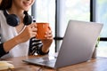 Beautiful young asian woman relaxes sipping a coffee while working on laptop. cropped Royalty Free Stock Photo