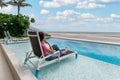 Beautiful young asian woman relaxing and sunbathing on lounge chair in swimming pool on tropical sea Royalty Free Stock Photo