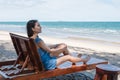 Beautiful young asian woman relaxing and sunbathing on wooden lounge on the beach in tropical sea Royalty Free Stock Photo