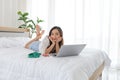 Beautiful young Asian woman relaxing and using a laptop on her bed Royalty Free Stock Photo