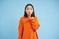 Beautiful young asian woman sends air kiss on her palm, kissing you, standing over blue background Royalty Free Stock Photo