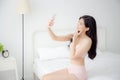 Beautiful young asian woman sexy in underwear talking a selfie on smartphone for social network in the bedroom Royalty Free Stock Photo